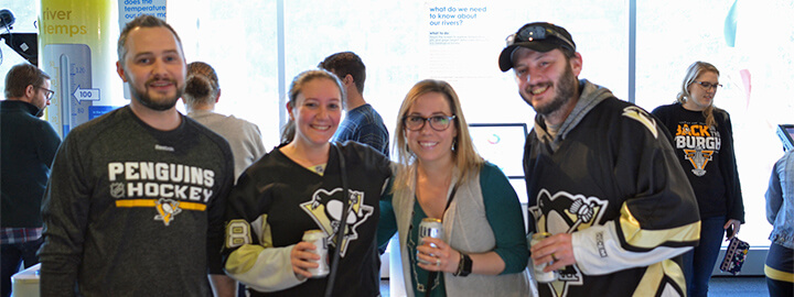 Young adults wearing Penguins jerseys and holding drinks