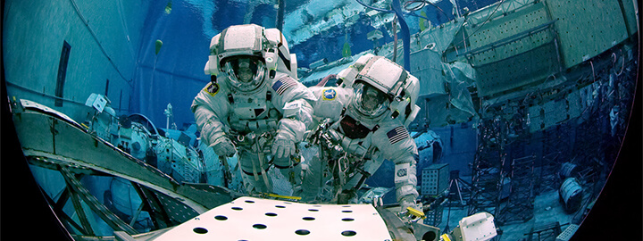 Two astronauts training under water.