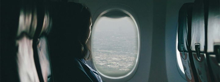 A woman seated on a plane, looking out the window
