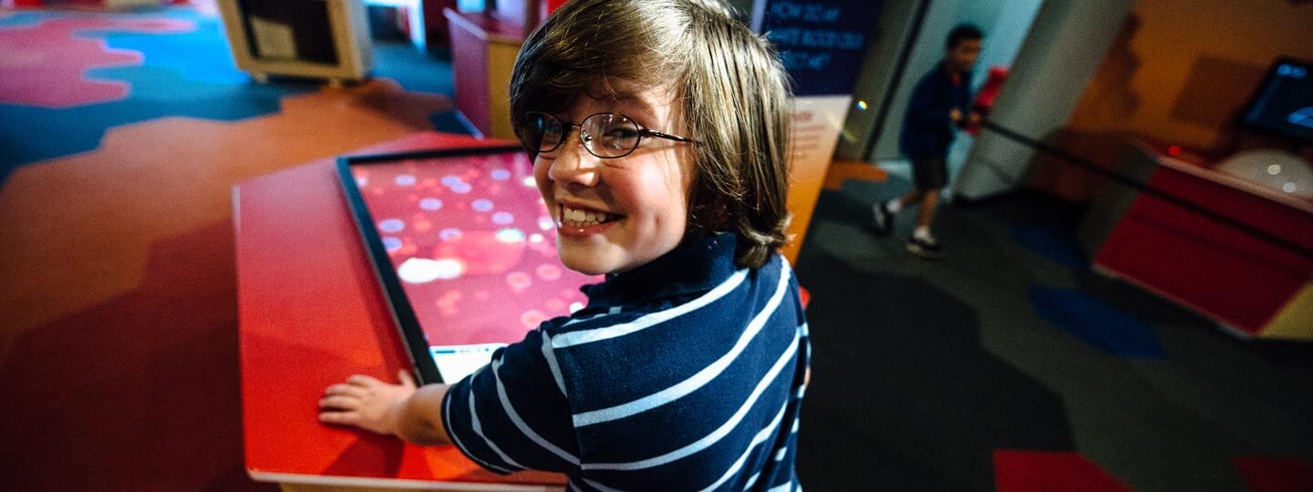 A kid looking over the shoulder while smiling learning about blood off of a screen