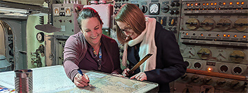 Two women looking at a map inside a submarine
