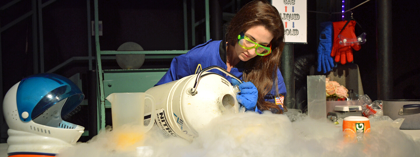 A live theater demonstration of a woman pouring liquid Nitrogen