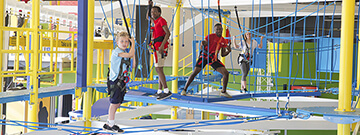 Three boys and a girl balancing on the ropes in SportsWorks 