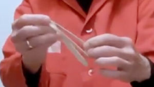 Hand holding a popsicle stick and rubber band
