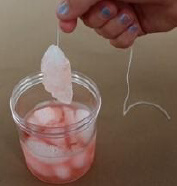 Hand holding a string with ice on the end