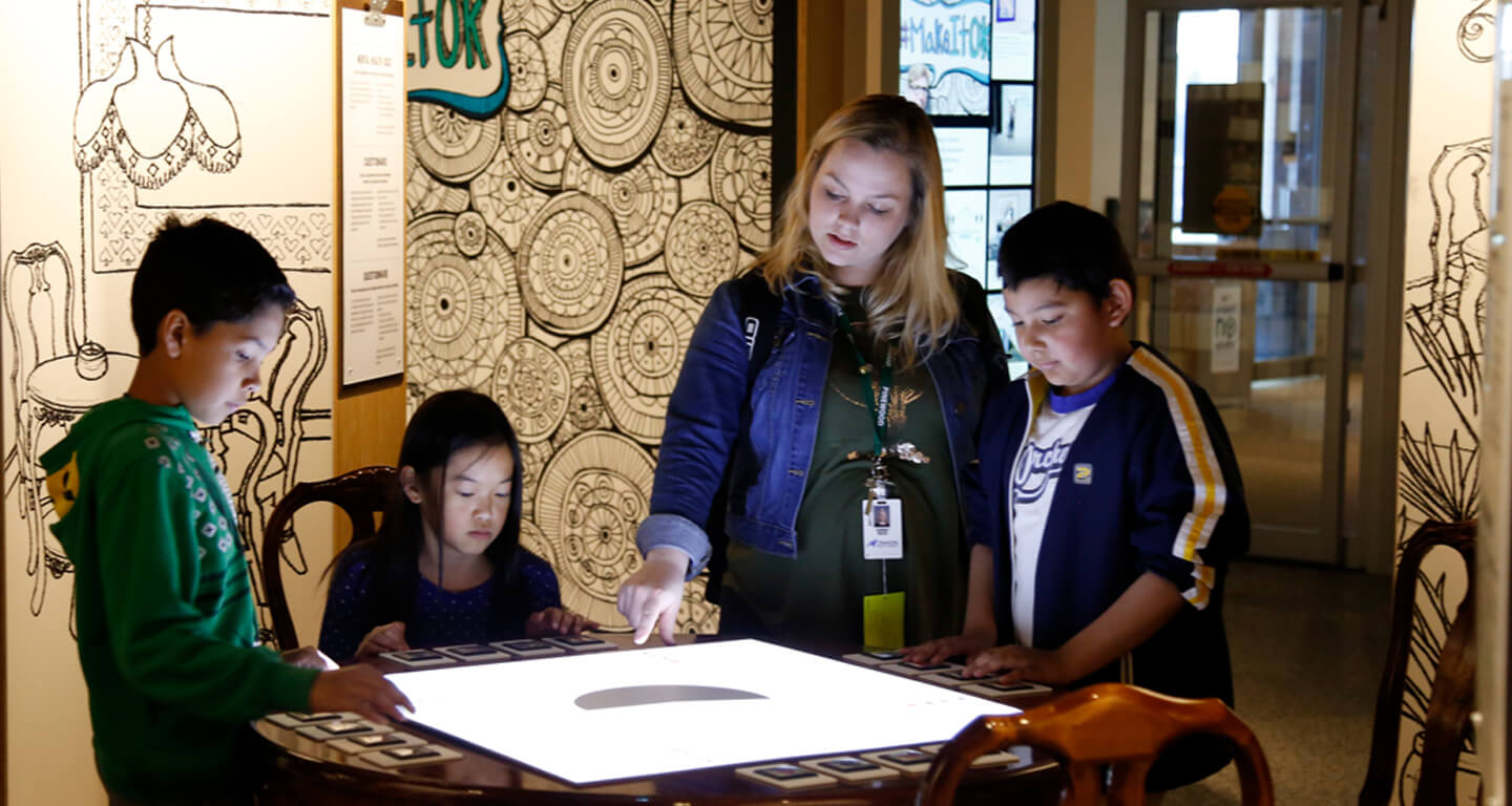 A woman and children looking at an interactive table screen