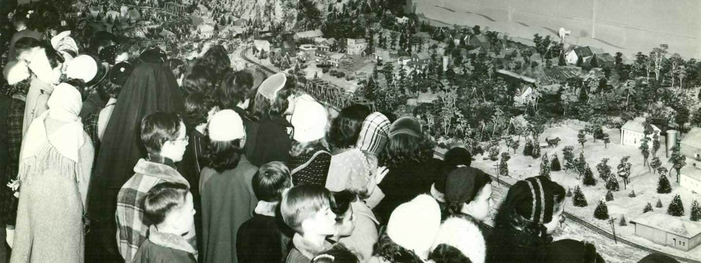 A historic photo of a group of people looking at the Miniature Railroad and Village