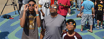 People wearing protective glasses looking up at an eclipse
