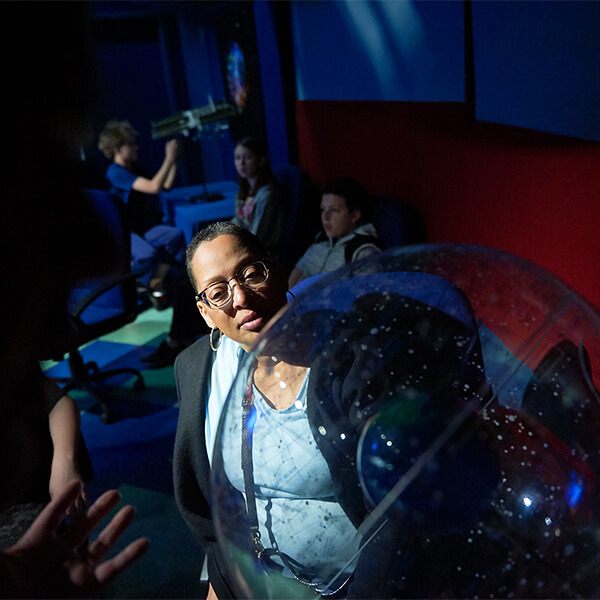 Guest looking at a plastic clear sphere with constellations