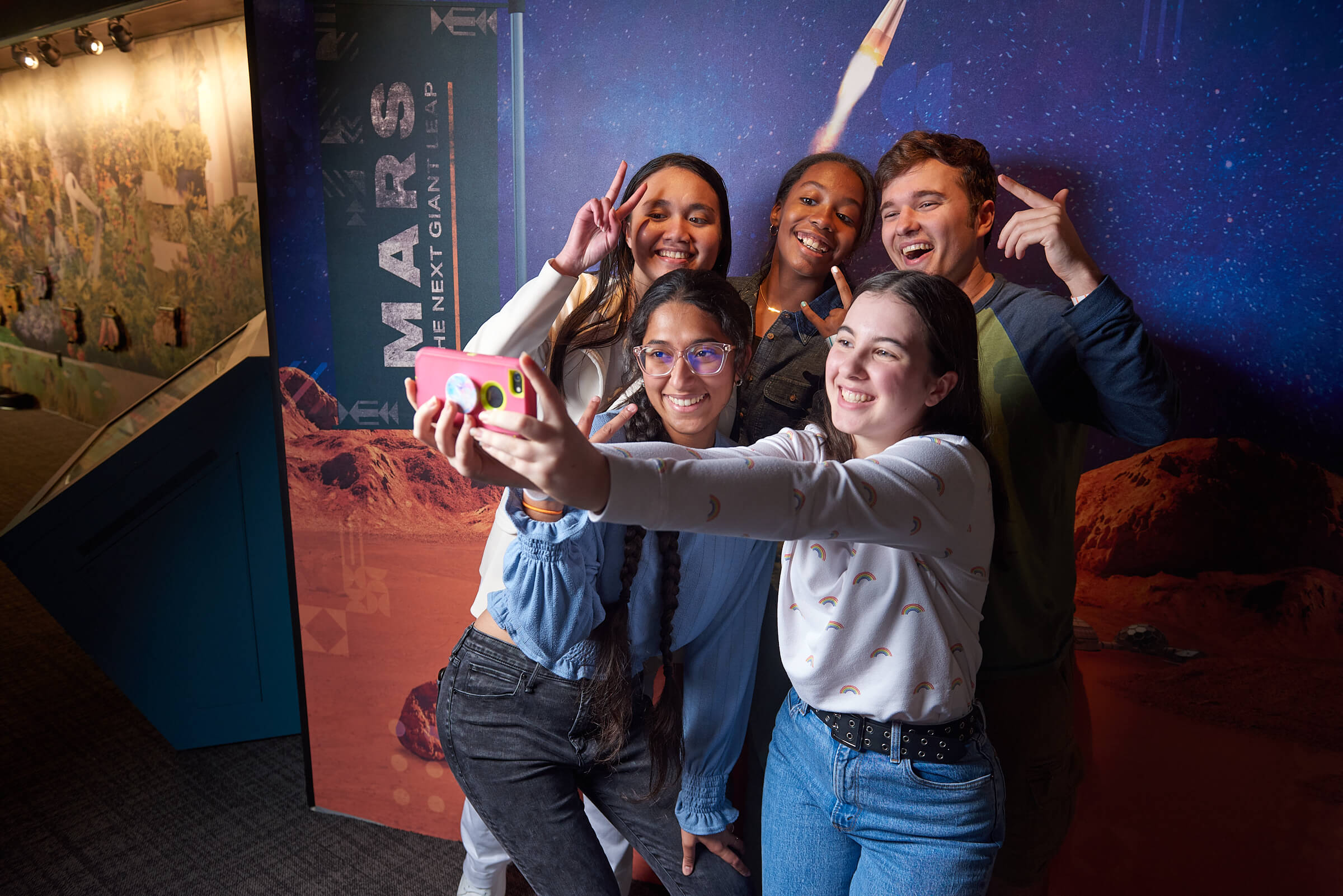 A group of teens taking a selfie in front of the Mars exhibit