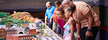 A mother smile as her family of four looks at the railroad display in awe