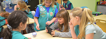 A group of girl scouts collaborate to program a tiny round robot called Sphero
