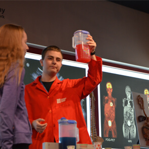 Staff member demonstrating with container filled with red liquid
