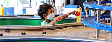 Boy wearing protective mask playing at a water table