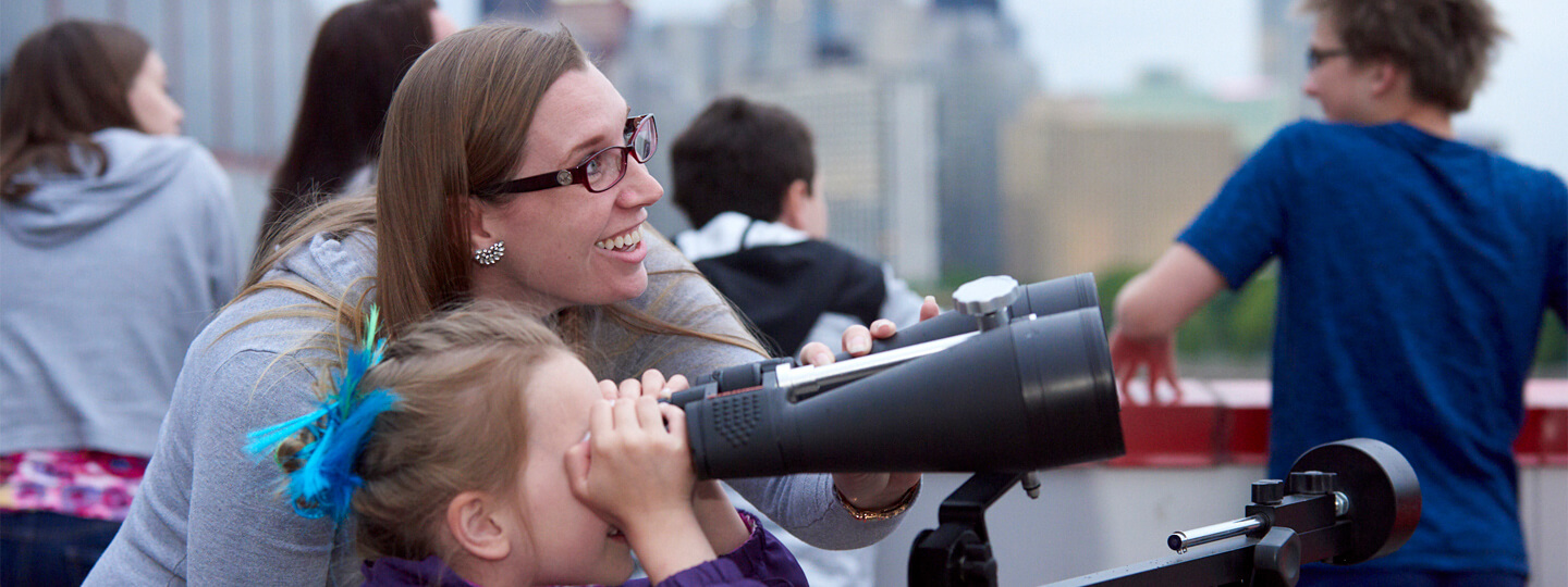 Mother with child looking through large binoculars