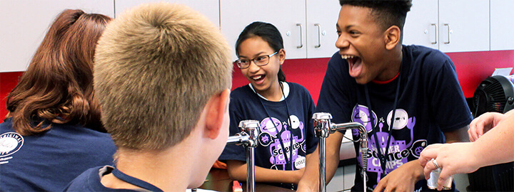 Students laughing around a classroom sink