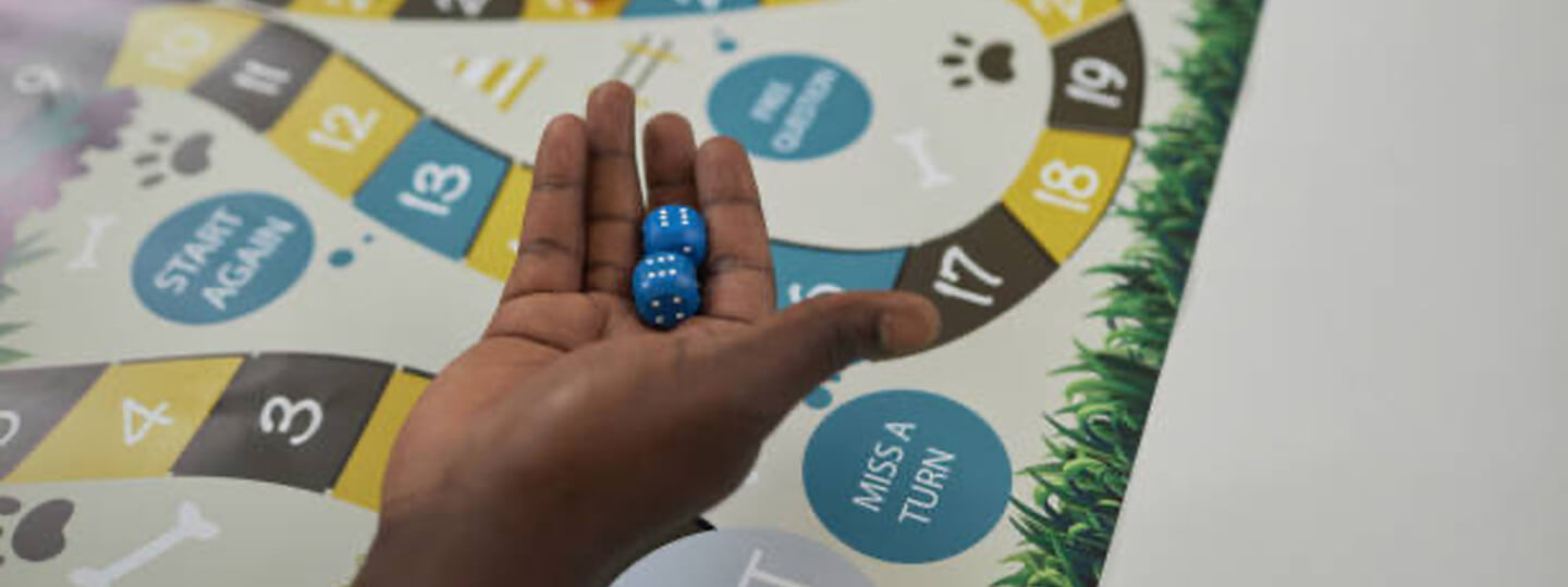 Hand above a board game holding dice