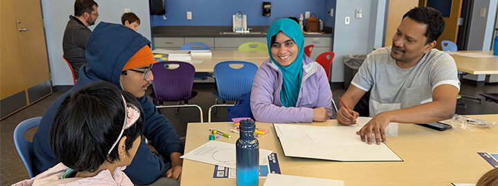 A group of people at a table with papers and art supplies.